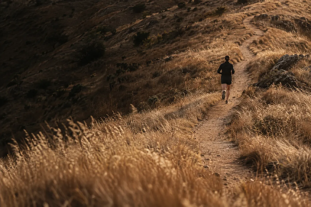 Illustrative runner photograph on a warm, grassy trail.